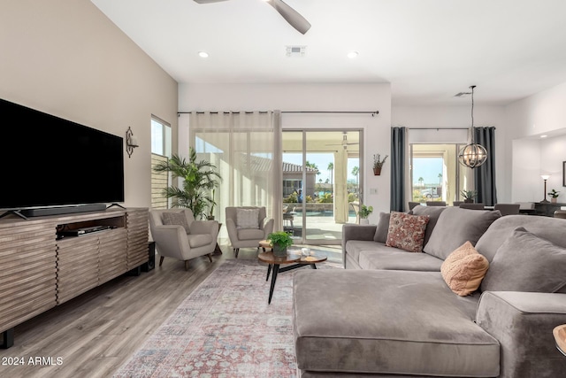 living room featuring light wood-type flooring and ceiling fan with notable chandelier