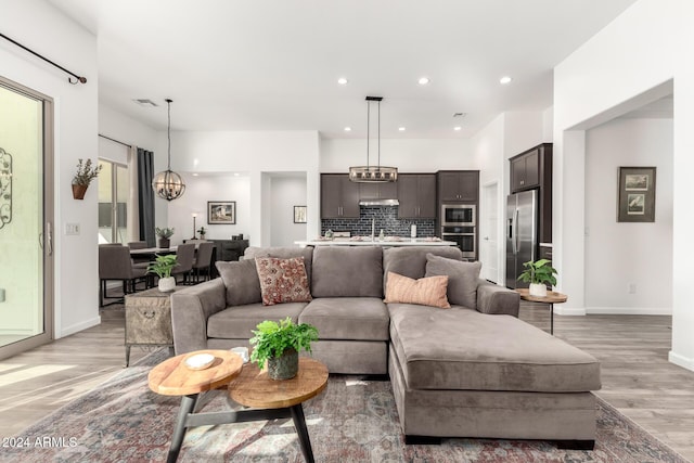 living room with light wood-type flooring and a chandelier