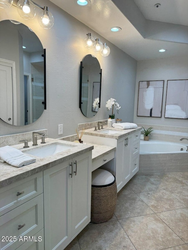 bathroom with a bath, tile patterned floors, two vanities, and a sink