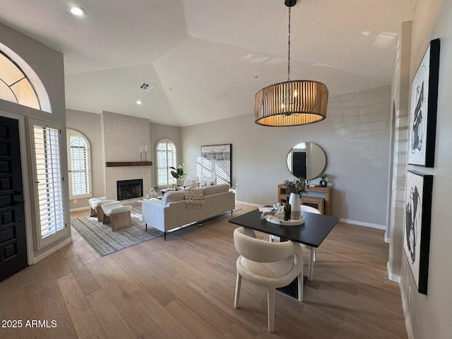 living area featuring visible vents, wood finished floors, a fireplace, baseboards, and vaulted ceiling