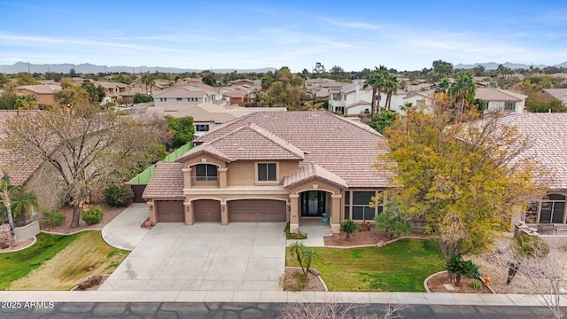 view of front of house with a mountain view, a garage, a tiled roof, stucco siding, and a front yard