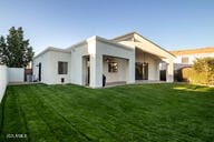 rear view of property featuring a yard and a fenced backyard