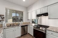 kitchen featuring under cabinet range hood, stainless steel appliances, and light countertops