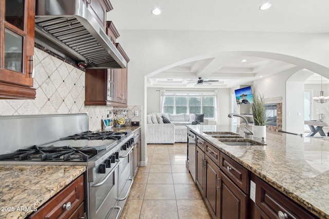 kitchen with backsplash, extractor fan, arched walkways, stainless steel appliances, and a sink