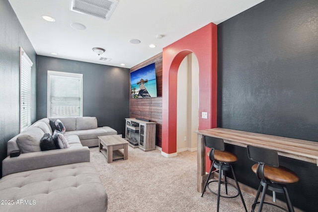 living area with visible vents, baseboards, light colored carpet, and an accent wall