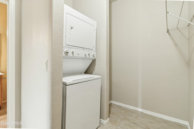 laundry room with stacked washer and dryer and light hardwood / wood-style floors