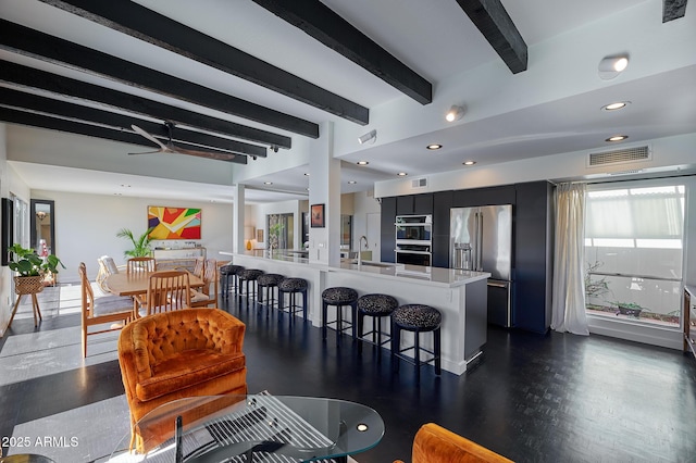 kitchen featuring sink, a kitchen breakfast bar, kitchen peninsula, double oven, and beam ceiling