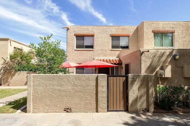 view of front of house with a gate, a fenced front yard, and stucco siding