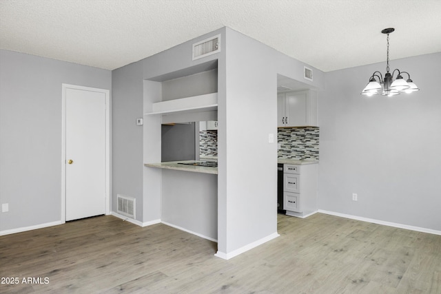 kitchen featuring visible vents, light wood-type flooring, and tasteful backsplash