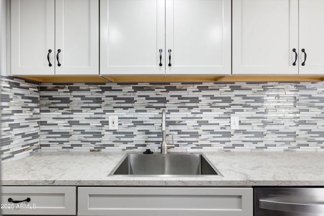 kitchen with a sink, decorative backsplash, white cabinetry, and dishwasher