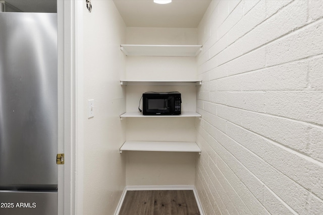 interior details featuring freestanding refrigerator, baseboards, black microwave, and wood finished floors