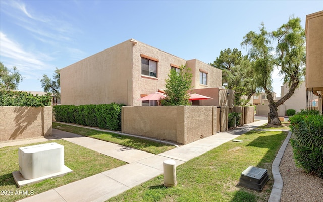 view of side of home featuring a yard, fence, and stucco siding