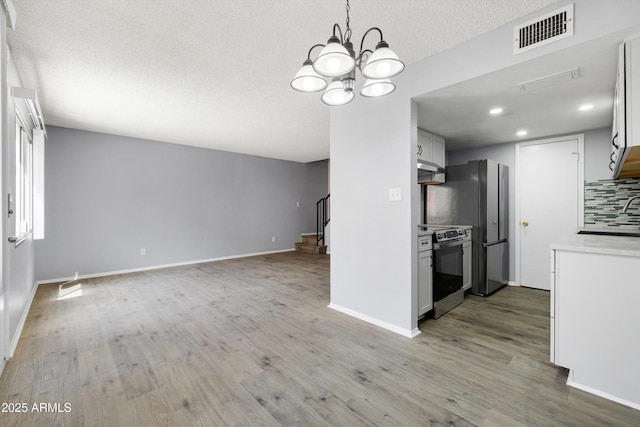 kitchen featuring electric range, a textured ceiling, visible vents, light countertops, and open floor plan