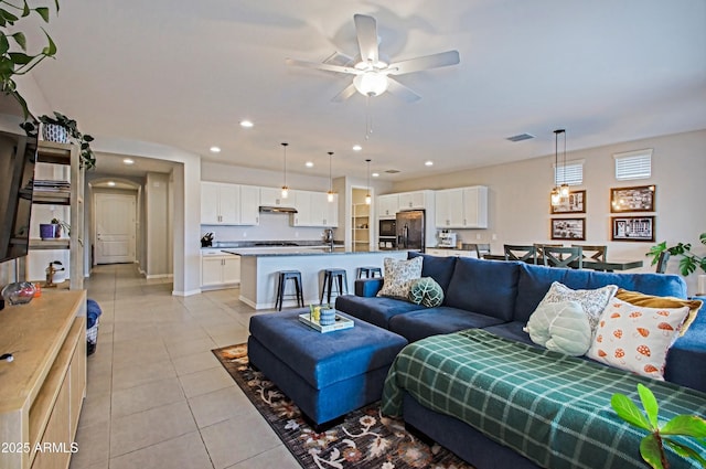 living area featuring arched walkways, light tile patterned flooring, a ceiling fan, and recessed lighting