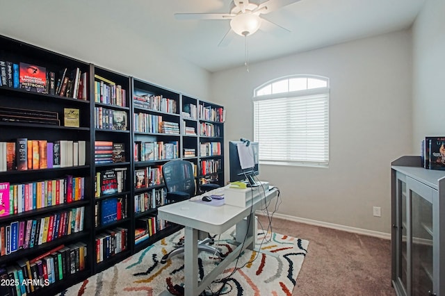 carpeted office space with a ceiling fan and baseboards