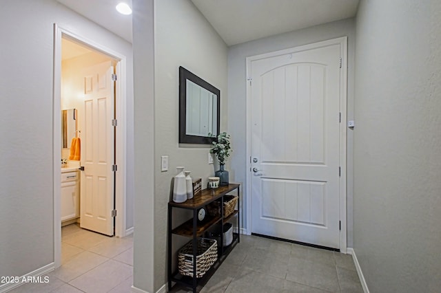 entryway with light tile patterned flooring and baseboards