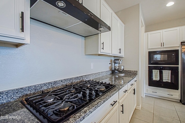 kitchen with white cabinets, light tile patterned flooring, dark stone counters, black appliances, and extractor fan