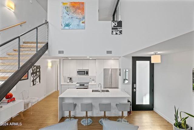 kitchen with stainless steel appliances, white cabinets, sink, and light wood-type flooring