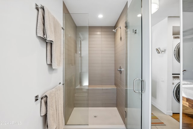 bathroom featuring wood-type flooring, stacked washer / dryer, and an enclosed shower