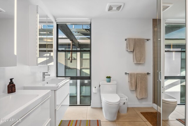 bathroom featuring walk in shower, vanity, tile patterned flooring, and toilet