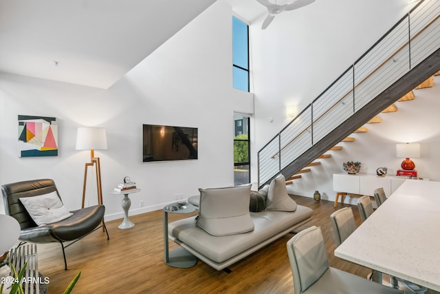 living room with a towering ceiling, hardwood / wood-style floors, and ceiling fan