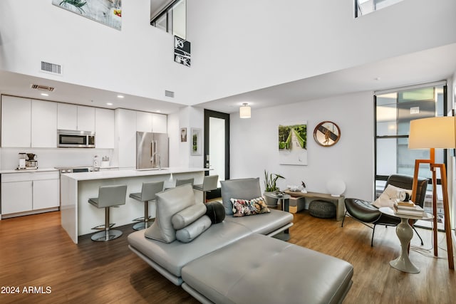 living room featuring dark wood-type flooring and a towering ceiling