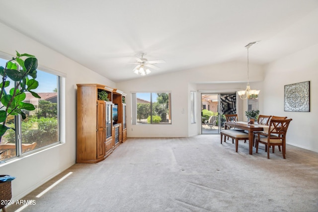 carpeted dining room featuring ceiling fan with notable chandelier and vaulted ceiling