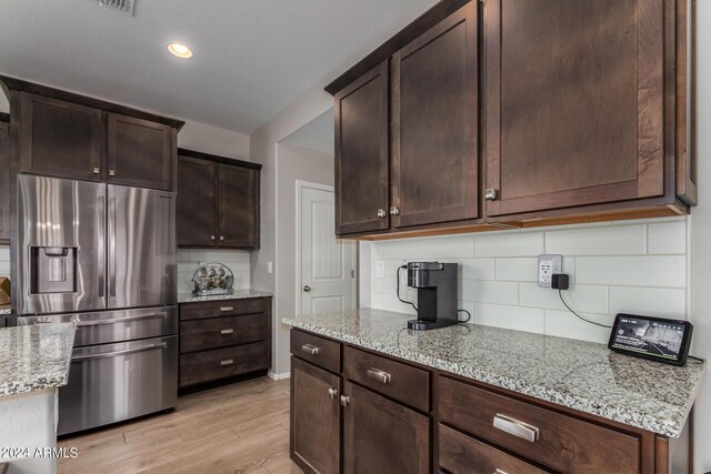 kitchen with stainless steel appliances, sink, light hardwood / wood-style floors, light stone countertops, and ceiling fan with notable chandelier