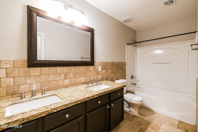 24163 N Cotton Cir, Florence, AZ 85132 - bathroom featuring toilet, tub / shower combination, tile walls, double vanity, and stone tile floors