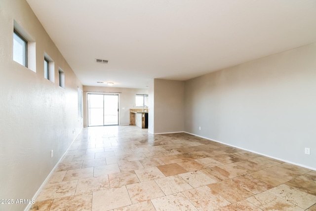 24163 N Cotton Cir, Florence, AZ 85132 - unfurnished living room with healthy amount of natural light, baseboards, and light stone finish floors