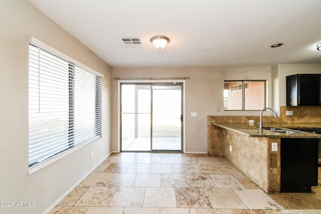 24163 N Cotton Cir, Florence, AZ 85132 - kitchen featuring a sink, dark stone counters, baseboards, and a peninsula