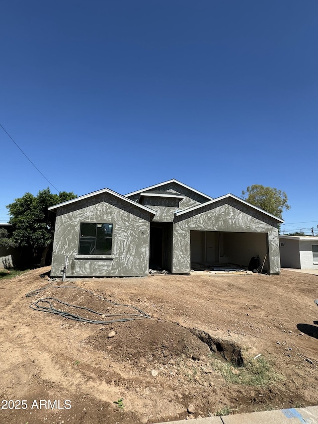 unfinished property with a garage, driveway, and stucco siding
