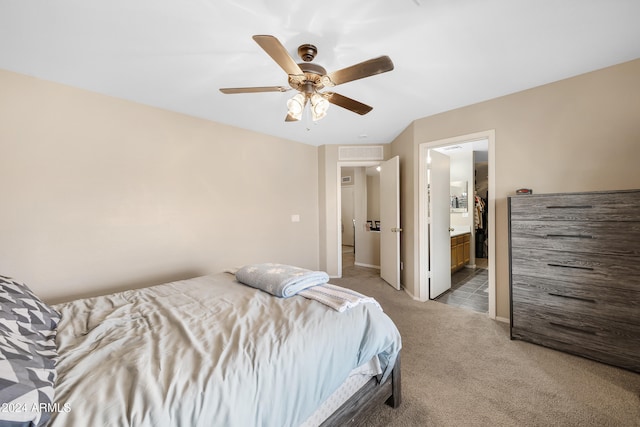 bedroom with ceiling fan, light colored carpet, and ensuite bathroom