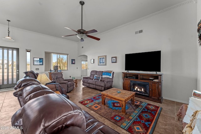 tiled living room with a towering ceiling, ceiling fan, and ornamental molding