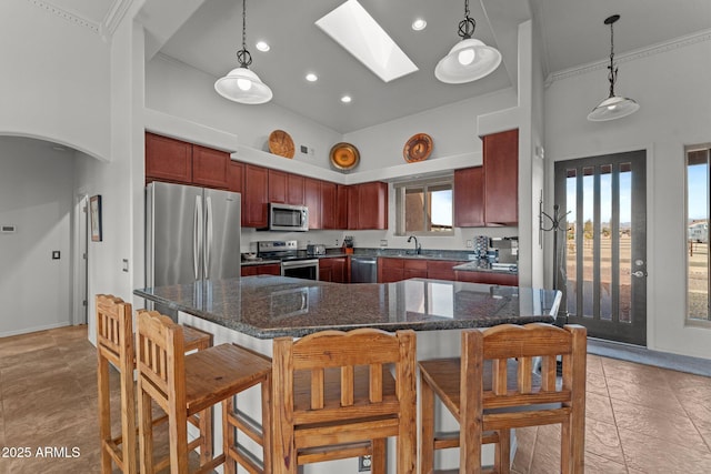 kitchen featuring stainless steel appliances, a center island, a towering ceiling, and decorative light fixtures