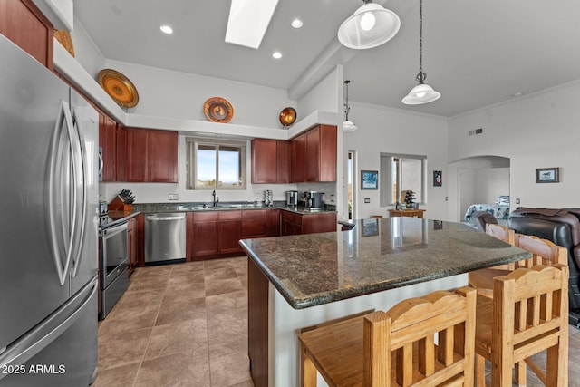 kitchen featuring pendant lighting, a skylight, stainless steel appliances, sink, and a breakfast bar