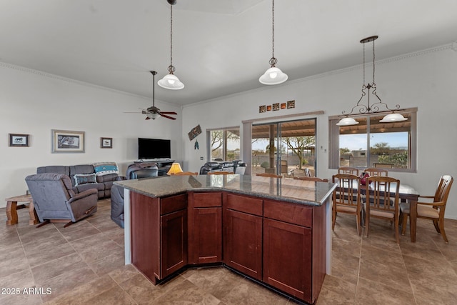 kitchen with decorative light fixtures, a kitchen island, ceiling fan, and ornamental molding