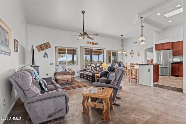 living room with ceiling fan, a high ceiling, a skylight, and ornamental molding