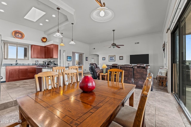 dining area with a skylight, light tile patterned flooring, and ceiling fan