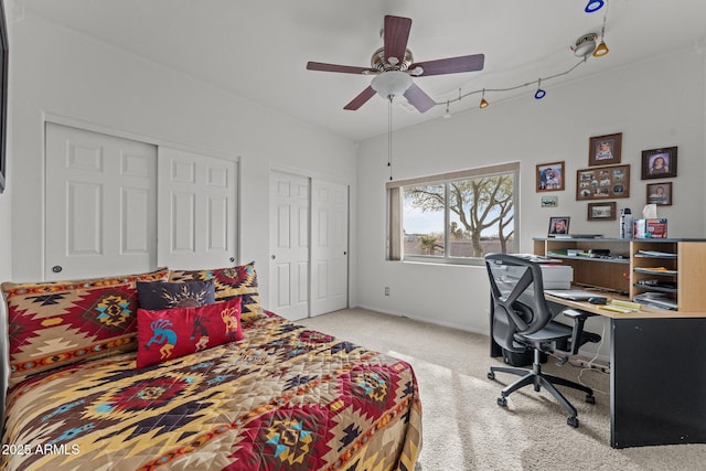 carpeted bedroom with ceiling fan and two closets