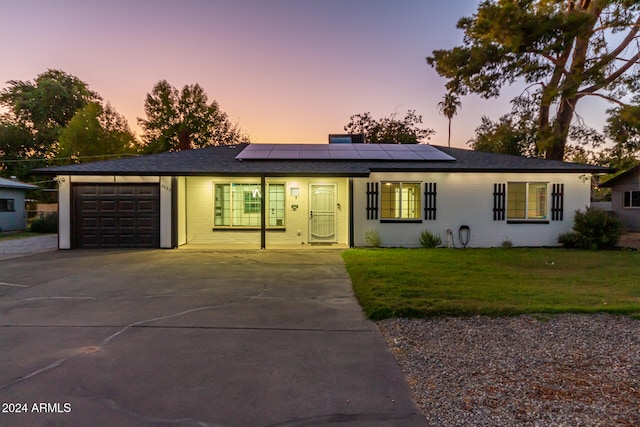 view of front facade featuring a garage, a yard, and solar panels