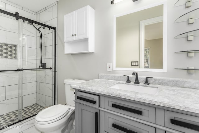 bathroom featuring a shower with door, vanity, and toilet