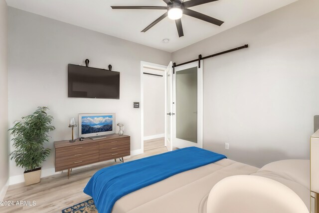 bedroom featuring a barn door, ceiling fan, and light wood-type flooring