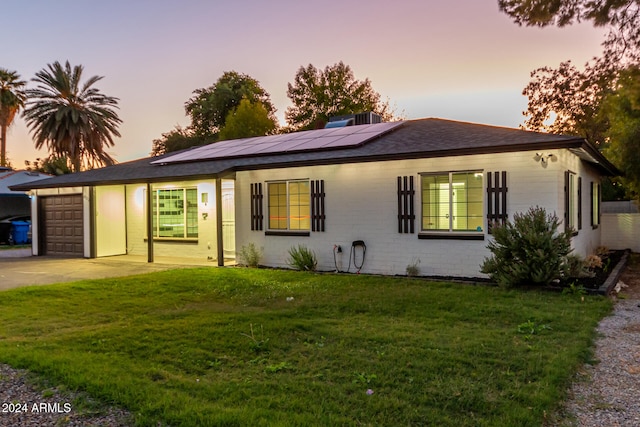 single story home featuring a garage, a yard, and solar panels