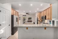 14687 W Amelia Ave, Goodyear, AZ 85395 - kitchen with stainless steel microwave, a peninsula, a kitchen breakfast bar, light tile patterned floors, and recessed lighting