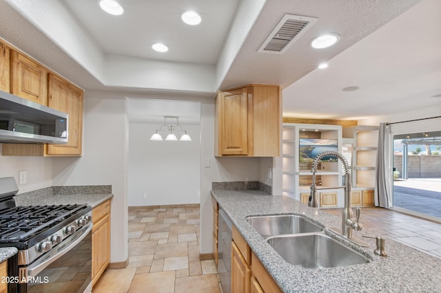 kitchen with light stone counters, visible vents, light brown cabinetry, a sink, and appliances with stainless steel finishes