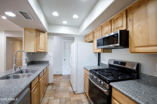 kitchen featuring visible vents, light brown cabinets, stainless steel appliances, and a sink