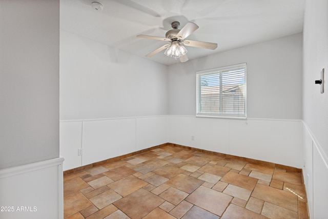 unfurnished room featuring a ceiling fan and wainscoting