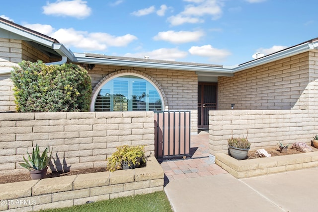 entrance to property with brick siding, a gate, and fence