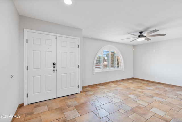 foyer featuring baseboards, stone finish flooring, and ceiling fan